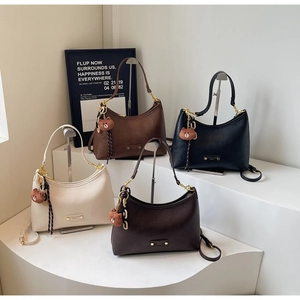Detail of four hobo bags in cream, brown, and black with cute bear charms on white display
