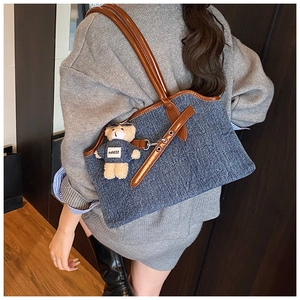 Detail der Denim-Tragetasche mit braunen Ledergriffen und einem süßen Bären-Anhänger