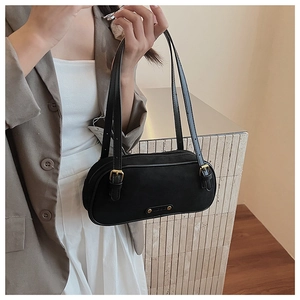 Detail of a vintage black baguette bag with gold hardware and dual adjustable straps