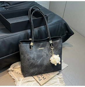 Close-up of grey marble texture tote bag with gold metal trim and plush sheep charm