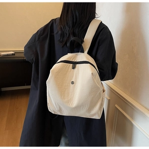 Zaino minimalista in tela da donna indossato, con tasche laterali e manico superiore