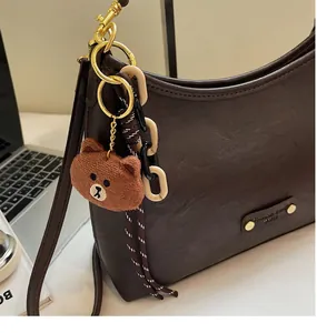 Close-up of a vintage dark brown leather shoulder bag with bear charm detail