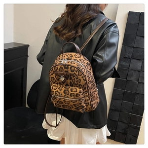 Détail du sac à dos léopard avec lanières en cuir brun et pendentif cœur en métal