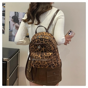 Détail d'un mini sac à dos en velours léopard avec nœud en cuir et pendentif cœur