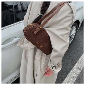 Detail view of brown suede Boston bag on model shoulder with golden metal hardware