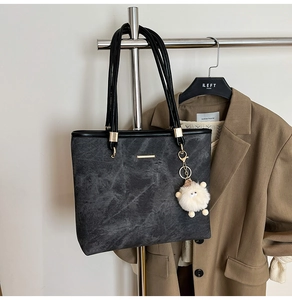 Detail view of stony grey textured tote bag with cute lamb charm on display rack