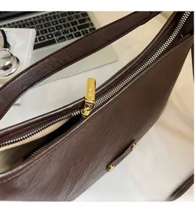 Detailed close-up of the smooth gold-toned zipper on a brown vintage leather shoulder bag