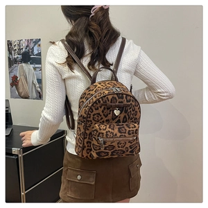 Détail d'un mini sac à dos en velours léopard avec nœud et pendentif sur un mannequin