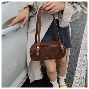 Detail of dark brown suede Boston bag featuring adjustable leather straps and metallic buckle