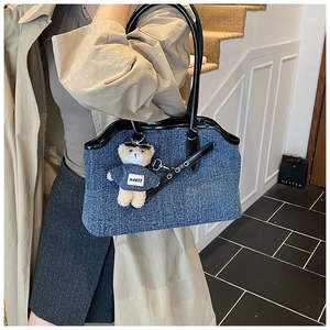 Blue denim tote bag with black glossy patent leather handles and a cute teddy bear charm