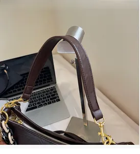 Detailed close-up of brown leather bag handle with gold hooks and decorative chain