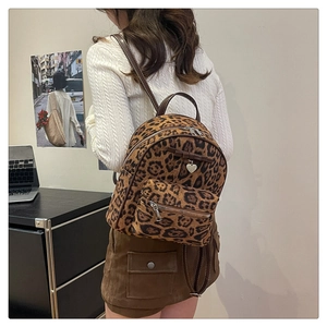 Détail macro du sac à dos léopard avec pendentif en cœur et nœud en cuir décoratif