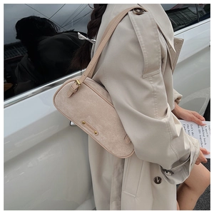 Detail of a beige suede Boston bag featuring metallic plaque and rivet decorations
