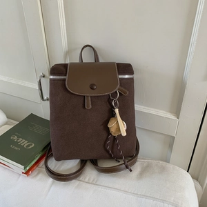 Dettaglio dello zaino vintage marrone opaco con finiture in pelle e ciondolo da baseball