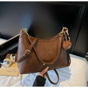 Brown vintage hobo bag detail with gold hardware and a cute bear charm pendant