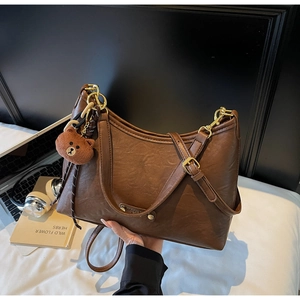 Detail view of brown vintage satchel with a plush bear charm and golden metal buckle