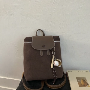 Dettaglio dello zaino vintage marrone opaco con ciondolo da baseball e cerniera argentata