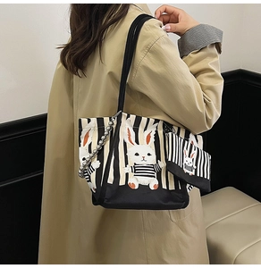 Dettaglio della borsa tote in tela a righe con coniglio e catena di perle argento