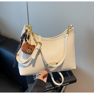 Detail of creamy white crescent bag with soft leather texture and golden metal buckle