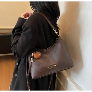 Detail of dark brown vintage crescent bag with a cute plush bear charm on the strap