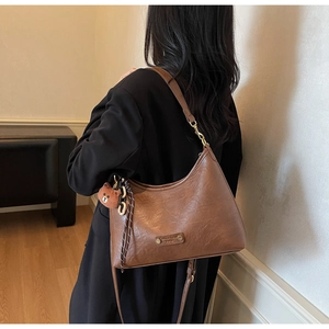 Detail of vintage brown PU leather hobo bag with teddy charm and textured finish