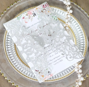 Macro view of silver glitter laser cut butterfly invitation on elegant pearl dish