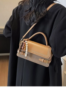 Minimalist two-tone brown square handbag with wooden beads shown on shoulder