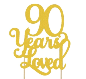 Close-up of glittery gold 90 Years Loved cake topper with wooden sticks for birthday party