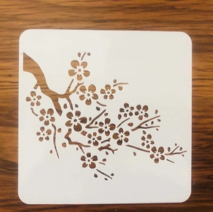 Detail of PET stencil with plum blossom branch pattern on a dark wood background