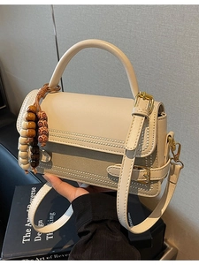 Chic beige crossbody square bag with bead details and ethnic bead charm accessory