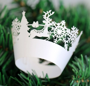 Intricate laser-cut white Christmas cupcake liners with snowflake and reindeer patterns