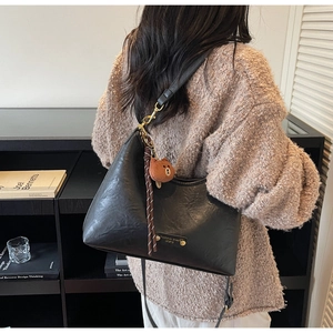 Detail of black matte leather hobo bag with gold hardware and plush bear charm