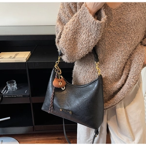 Detail view of retro black hobo bag with gold hardware and plush bear charm decoration