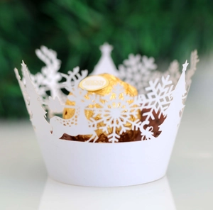 White laser-cut Christmas cupcake wrappers with snowflake and reindeer festive patterns