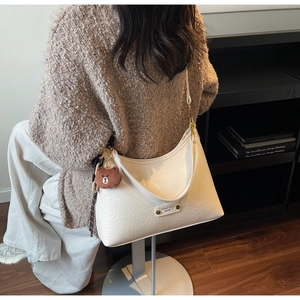 Detail of off-white pleated shoulder bag with brown bear charm and metal logo plate