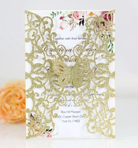 Detail of laser-cut butterfly wedding invitation with gold glitter texture and floral card