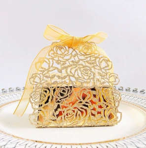 Detailed laser-cut rose pattern on golden glitter gift box with satin ribbon bow