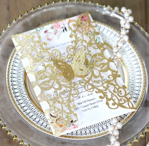 Detail showing laser-cut butterfly wedding invitation with gold glitter and floral inner