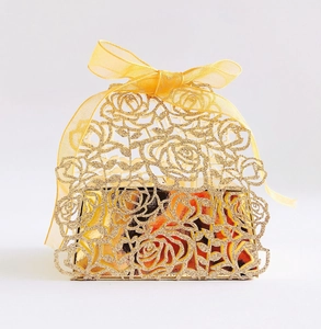 Detail of laser-cut rose patterns on a gold glitter gift box with a satin ribbon bow