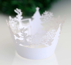 Close-up of white laser-cut Christmas cupcake wrappers with reindeer and snowflake patterns