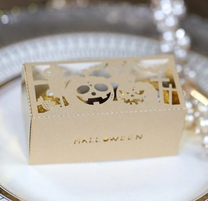 Elegant gold laser-cut Halloween gift box with pumpkin and bat patterns on a white plate