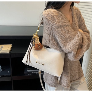 Detail of white PU leather shoulder bag with plush bear charm and chain decoration