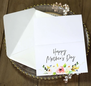 Close-up of Mother's Day floral card and envelope on a wooden desk with elegant decor