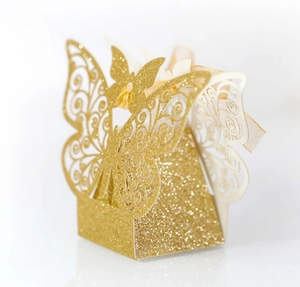 Close-up of laser-cut butterfly candy box with gold glitter finish and cream silk ribbon