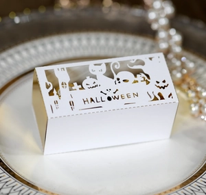 Hollow out Halloween candy box with pumpkin and black cat design on white ceramic plate