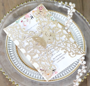 Detailed laser cut butterfly wedding invitation with gold glitter texture and floral insert
