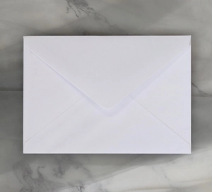 Close-up of a minimalist white V-flap paper envelope on a luxury marble and tulle backdrop