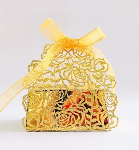 Macro shot of laser-cut rose patterns on a gold glitter favor box with a ribbon