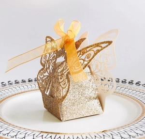 Detailed laser-cut gold glitter butterfly candy box with a soft orange silk ribbon bow