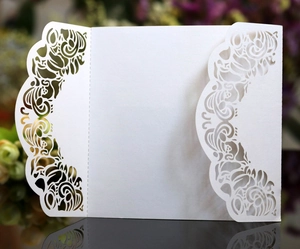 Elegant white laser-cut wedding invitation card with intricate scroll pattern on mirror base